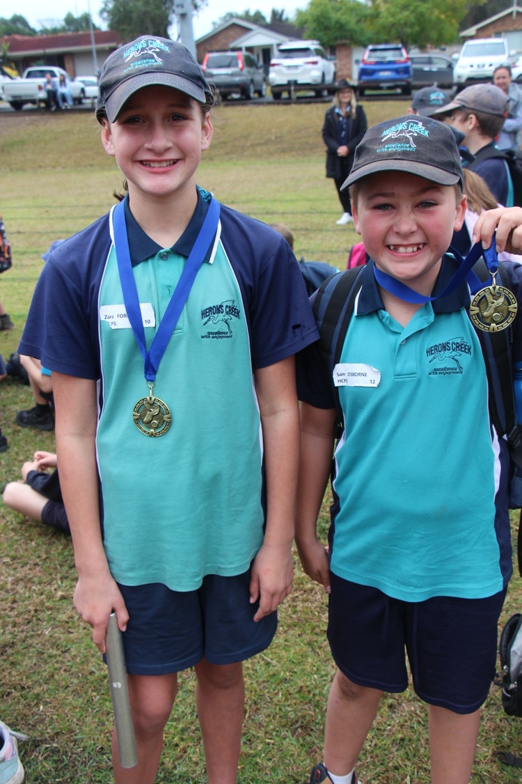 Two smiling students at the athletics carnival with their Age Champion medals