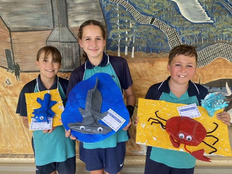 Students holding up their art works -paper mache Axolotl, Hammerhead Shark and crab