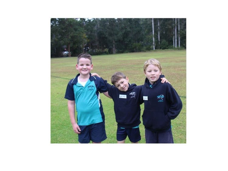 Three students smiling together at the athletics carnival